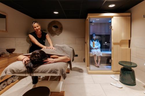 a woman sitting on a bed in a salon at Keystone Hôtel & Spa in Lyon