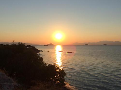 a sunset over the water with the sun setting at Isidora Hotel in Agia Marina Aegina
