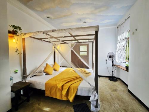 a bedroom with a canopy bed with yellow pillows at Star Hill Villa in Tangalle