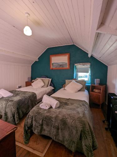 a bedroom with two beds and a blue wall at 2 Bedroom Cottage By Travel Lets Self Catering Accommodation Donegal With Sea View in Fanad