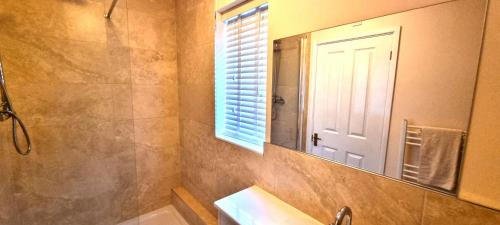 ein Badezimmer mit Waschbecken, Spiegel und Fenster in der Unterkunft Sand Dunes in Perranporth