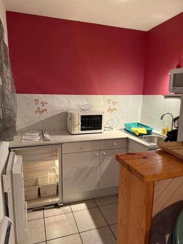 Il comprend une cuisine dotée de murs rouges et d'un réfrigérateur blanc. dans l'établissement Primavera, à Luz-Saint-Sauveur