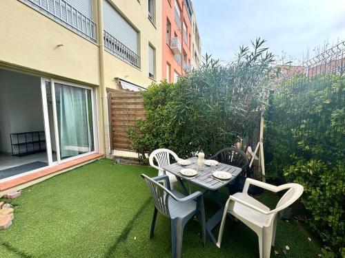 un patio avec une table et des chaises sur l'herbe dans l'établissement Appartement - Cap d'Agde, au Cap d'Agde
