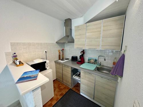 une petite cuisine avec un évier et un micro-ondes dans l'établissement Appartement - Cap d'Agde, au Cap d'Agde
