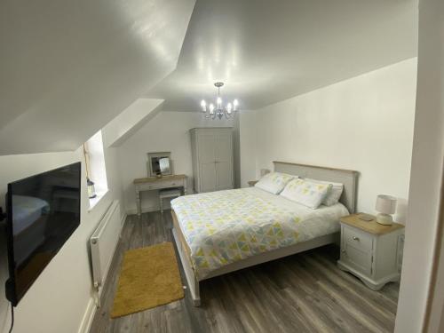 a white bedroom with a bed and a chandelier at Mountain View Retreat in Rostrevor With hot Tub in Newry