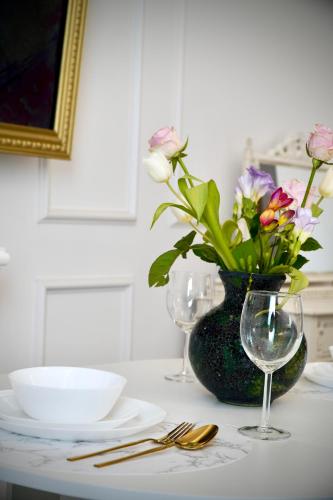 a table with a vase of flowers and two glasses at Ludovic Luxury Suite in Bucharest