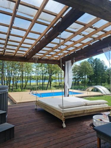 a large bed on a wooden deck with a roof at Poilsiaviete Vakaris in Gudeliai