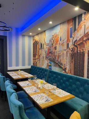 a row of tables in a restaurant with a painting at Hotel Les Jardins Carol in Bucharest