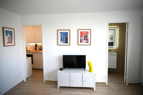 un salon avec une télévision sur un mur blanc dans l'établissement Studio Paris, à Ivry-sur-Seine