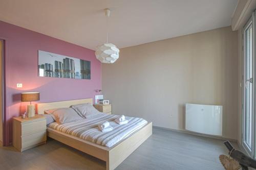une chambre avec un lit et un mur rose dans l'établissement Appartement face à la mer, à Cabourg