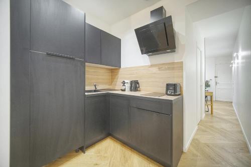 - une cuisine avec des placards noirs et un évier dans l'établissement charmant 2 pieces proche plage du midi A1B266, à Cannes