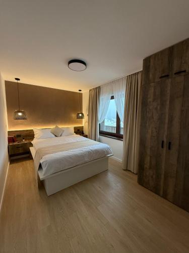 a bedroom with a large bed and a large window at Massif Carpathian Call in Poiana Brasov