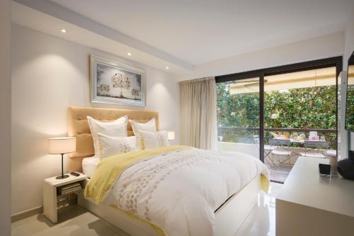 une chambre avec un lit et une grande fenêtre dans l'établissement Carlton & Croisette, chic & entièrement rénové, 2 chambres & 2 sdb, à Cannes