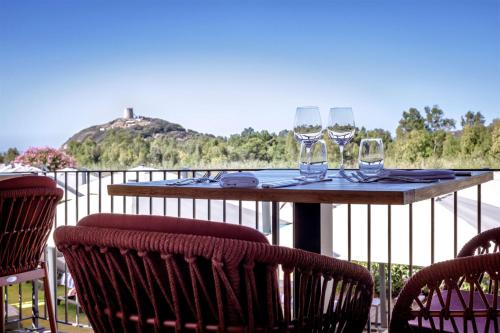 a table with two wine glasses on a balcony at Veridia Resort Sardinia, a member of Radisson Individuals in Chia