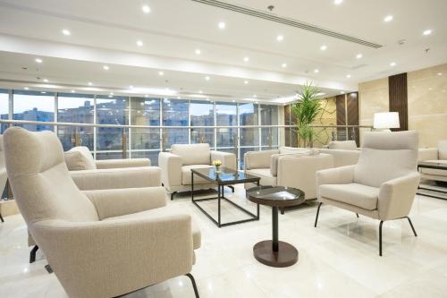 a waiting room with white chairs and tables and windows at Hotel SDU BOUTIQUE in Al Madinah