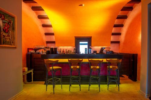 a bar with stools in a room with orange walls at Phoenicia Express Hotel in Bucharest