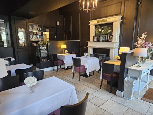 a restaurant with white tables and chairs and a fireplace at The Old Bank Bruff Family Town House in Bruff