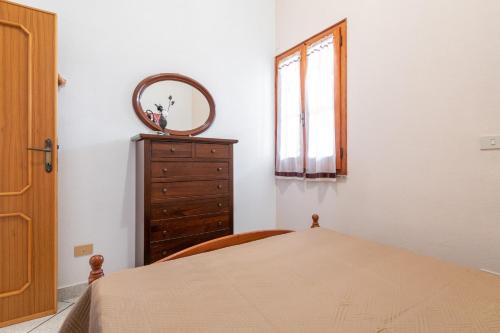 a bedroom with a dresser and a mirror and a bed at Villa Lidia vicino al mare in Solanas
