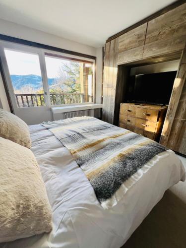 une chambre avec un grand lit et une grande fenêtre dans l'établissement Fairway, à Megève