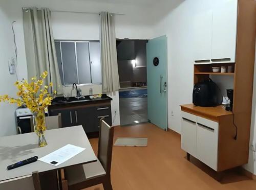 a kitchen with a table with a vase of flowers on it at Ap 3 Ouro Pret com piscina aquecimento solar e churrasqueira in Ouro Preto