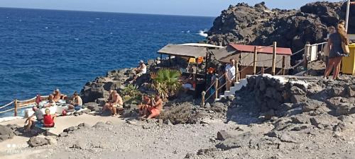 eine Gruppe von Menschen, die am Strand in der Nähe des Ozeans sitzen in der Unterkunft Sweet Life in Costa Del Silencio