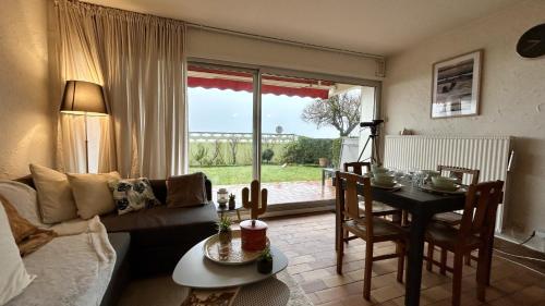 un salon avec un canapé et une table ainsi qu'une salle à manger dans l'établissement JArdin sur Baie, appartement vue mer, au Crotoy