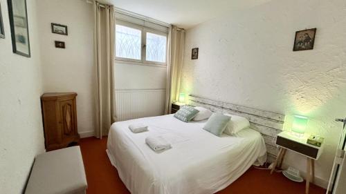 une chambre avec un lit blanc et une fenêtre dans l'établissement JArdin sur Baie, appartement vue mer, au Crotoy