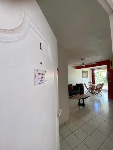 a kitchen and living room with a white wall at CoCoKreyol - " ARUBA" in Les Trois-Îlets