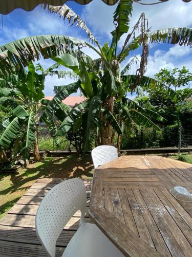 a wooden table with two chairs and a palm tree at CoCoKreyol - " ARUBA" in Les Trois-Îlets