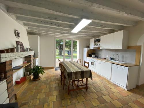 une cuisine avec des armoires blanches et une table avec des chaises dans l'établissement Gîte de la maison de Triboulet- Amboise, à Pocé-sur-Cisse