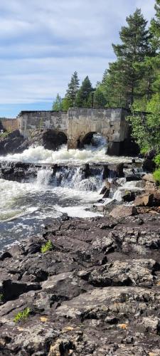 a bridge over a river with water rushing over rocks at Villa Stone House Lappland in Norsjö