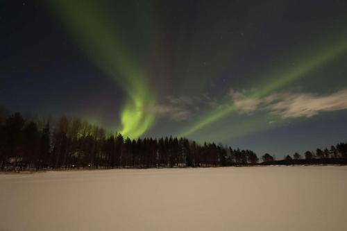 a group of green lights in the sky over a snowy field at Villa Stone House Lappland in Norsjö