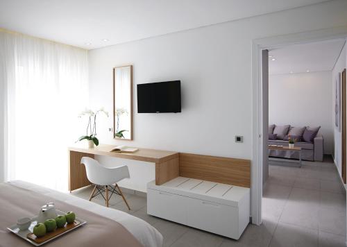 a bedroom with a bed and a desk with a television at Atlantica Marmari Beach in Marmari