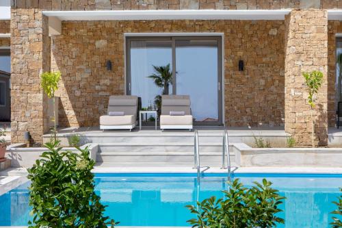 a house with a swimming pool and two lounge chairs at Ajul Luxury Hotel & Spa Resort, a Registry Collection Hotel in Agia Paraskevi