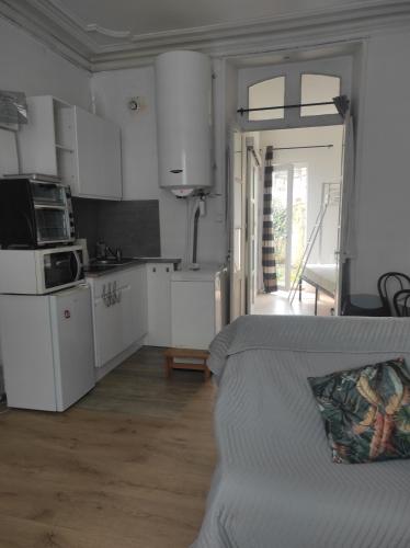 une cuisine avec des armoires blanches et un canapé dans une pièce dans l'établissement Cosy dreams 24H du Mans avec jardin, au Mans