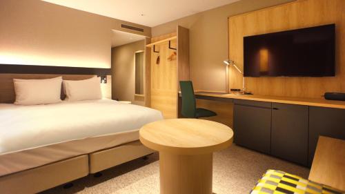 a bedroom with a bed and a desk with a television at ANA Crowne Plaza Niigata by IHG in Niigata