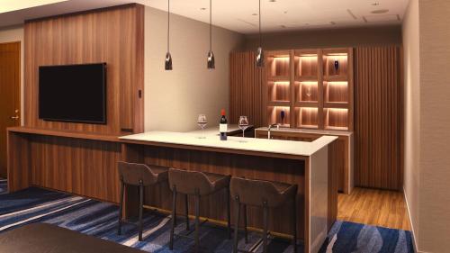 a kitchen with a bar with chairs and a tv at ANA Crowne Plaza Niigata by IHG in Niigata