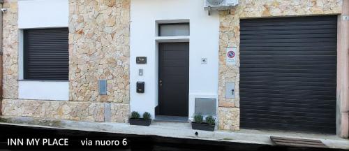 a building with two black garage doors on it at INN My Place in Selargius