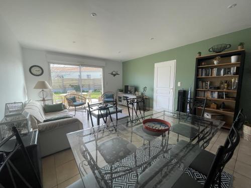 un salon avec une table en verre et des chaises dans l'établissement Les Alizes, à Givrand