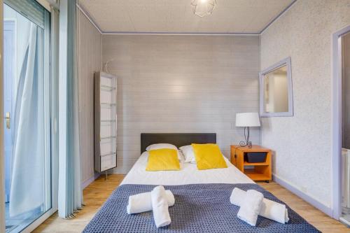 une chambre avec un grand lit avec des oreillers jaunes dans l'établissement Appartement St Arnaud, à Arcachon