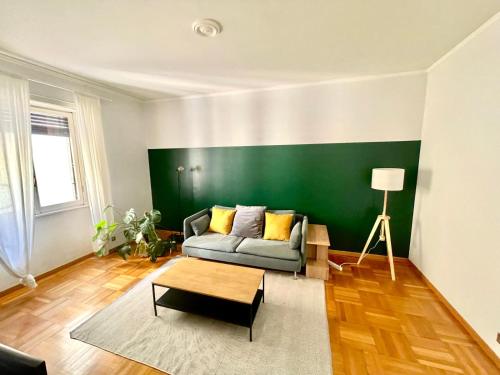 a living room with a couch and a green wall at Downtown Milan Chic Apartment - Quiet Retreat with Free WIFI & Air Conditioning in Milan