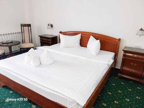 a bedroom with a bed with white sheets and pillows at Green Park Boutique Hotel in Focşani