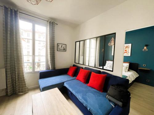 un salon avec un canapé bleu avec des coussins rouges dans l'établissement Appartement sur cour quartier Olympiades, à Paris