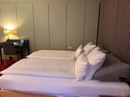 a bedroom with a bed with white sheets and pillows at Hotel Haus am Hochwald in Hahnenklee-Bockswiese