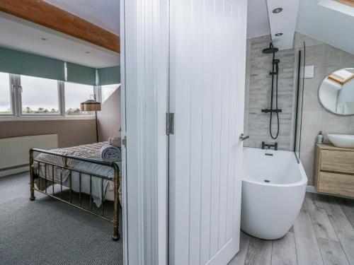 a bathroom with a tub and a sink and a bed at Willow Cottage in Carnforth