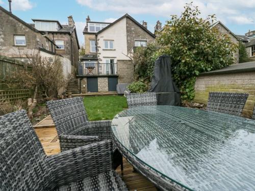 a patio with a glass table and chairs at Willow Cottage in Carnforth