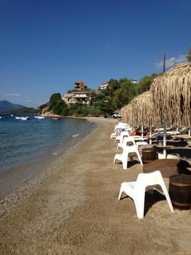 a beach with white chairs and umbrellas and the water at Ammos Beach in Glífa