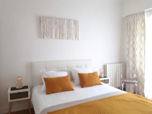 - un lit blanc avec des oreillers orange dans une chambre dans l'établissement Luxueux 3P en plein cœur de Nice, à Nice