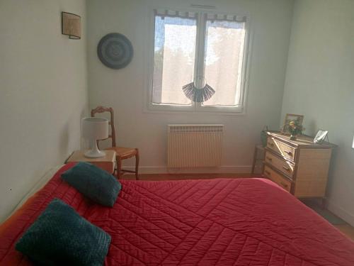 una camera da letto con un letto rosso e una finestra di Charmante maison près de la forêt de châtaigniers a Ceyrat