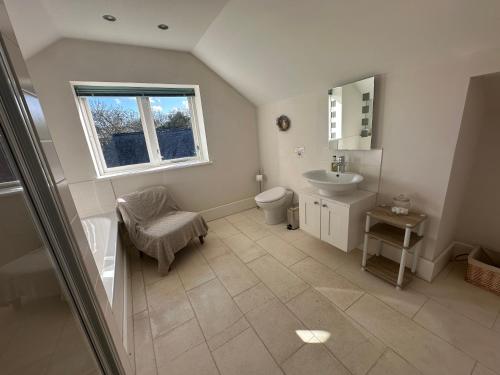 une salle de bain avec toilettes, lavabo et fenêtre dans l'établissement Penarvon House - Stunning Waterfront Escape with Games Room, à Manaccan